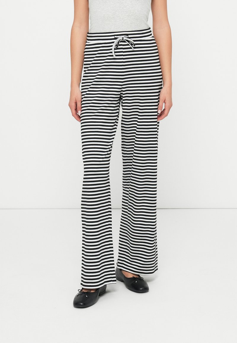 Pantalones de perna larga listrados em preto e branco, com cordão na cintura, feitos de um tecido suave, apresentando um ajuste relaxado e uma silhueta reta.