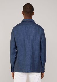 Camicia casual blu navy con tessuto strutturato, maniche lunghe e colletto classico. Presenta polsini con bottoni e un orlo dritto.