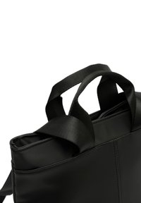 Črna sintetična torbica v obliki tote z dvema kratkima tekstilnima ročajema, pravokotne oblike, gladke teksture in vidno šivanjem ob šivih.