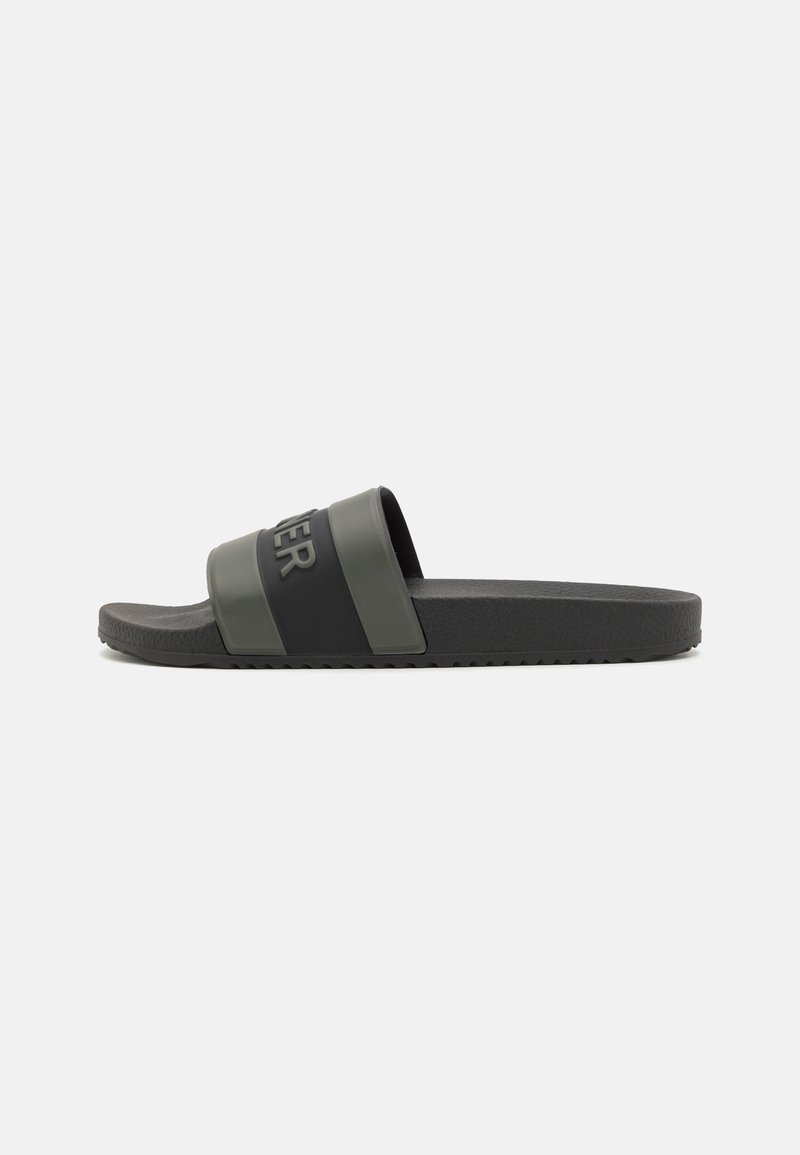 Sandalie negre și verzi, cu talpă texturată și accent logo pe curea. Talpă plată, material moale, design cu vârful deschis.
