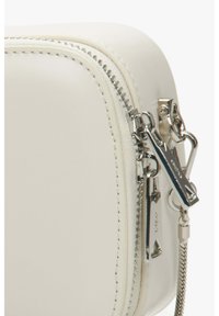 Bílá kožená taška na zip se stříbrnými detaily, hladkým povrchem a kontrastním prošíváním podél okrajů. Zip má poutko pro snadné uchopení.