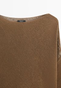 Maglione marrone lavorato a maglia con ampio scollo rotondo e etichetta visibile "Massimo Dutti Made in China" sul colletto interno.
