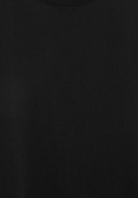 Sort t-shirt med rund hals og et lille, centralt placeret, hvidt cirkulært motiv, der ligner en stiliseret bølge eller spiral.