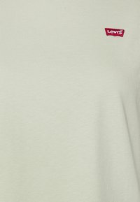 Světle zelené bavlněné tričko s červenou nášivkou loga Levi's. Tkanina má hladkou texturu a klasický kulatý výstřih.