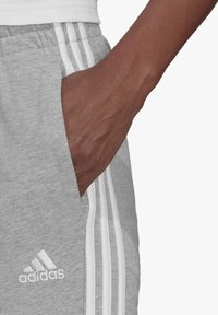 adidas Sportswear Spodnji deli trenirk - medium grey heather/white