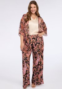 Květnatý outfit složený z průsvitného kimona a odpovídajících širokých kalhot v černých, růžových a fialových odstínech, pod kterým je hladký béžový top.