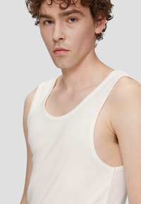 Witte katoenen tanktop met ruime armsgaten en een ronde halslijn. Soepele textuur, aansluitend ontwerp en geribbelde details langs de randen.