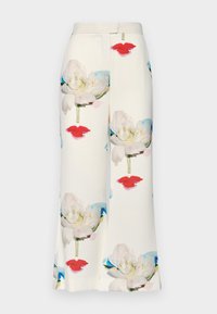 Pantalons en tissu blanc ornés d'un motif floral avec de grandes fleurs blanches et des lèvres rouges, texture lisse et coupe droite ajustée.