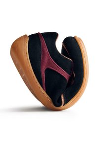 Chaussures slip-on en daim noir et bourgogne avec une semelle en caoutchouc brun texturé et des détails de couture contrastants. Design arrondi et de profil bas.