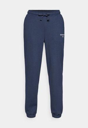Mørkeblå joggebukser laget av bomullsblanding, med elastisk linning med snor og ribbede mansjetter ved anklene. Logo trykt på siden.