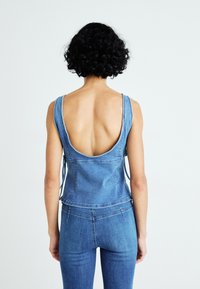 Denim top met een open rug en brede bandjes. Beschikt over blauwe stof, een gladde textuur en een getailleerde pasvorm, gecombineerd met bijpassende denim broek.