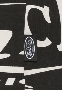 Black fabric featuring bold white lettering and a small woven tag with "Von Dutch Originals" logo. Smooth texture, casual design.