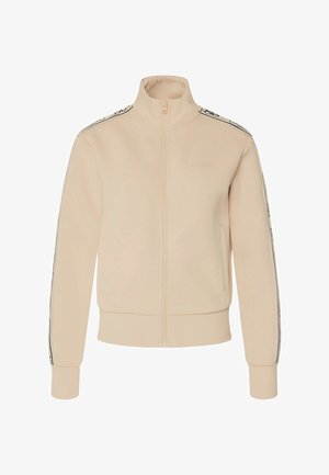 Giacca beige con cerniera realizzata in tessuto morbido, caratterizzata da un colletto alto, polsini e orlo a coste, con dettaglio logo e strisce laterali a contrasto.