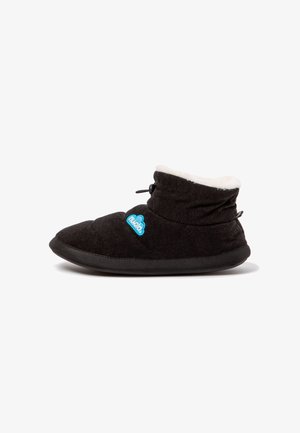 Botín tipo zapatilla negro con forro interior blanco y suave, puño elástico en el tobillo y un logo azul de nube en el lateral.