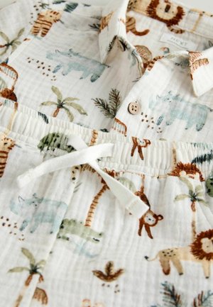 Kortærmet bomuldsskjorte med knapkrave, der har en hvid baggrund og farverige mønstre af dyr og palmetræer. Indeholder snøre i taljen.