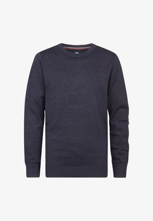 Tummansininen neule, jossa on pitkät hihat, pyöreä pääntie ja resorit, yhdistettynä vaaleanharmaisiin farkkuihin ja valkoisiin lenkkikenkiin mustilla yksityiskohdilla.