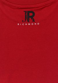 Červená bavlněná tričko s kulatým výstřihem, hladkým povrchem a černým logem s nápisem "JR" a "RICHMOND" tištěným níže.