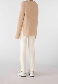 Vaaleanpunainen neulepaita, jossa on ribbikuvio, sivuhihoja ja se on yhdistetty kermaisiin housuihin ja hopeisiin urheilukenkiin.