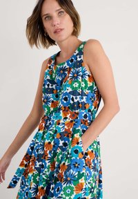 Rochie florală cu un model vibrant în nuanțe de albastru, verde, portocaliu și alb, cu un bust ajustat, decolteu rotund și buzunare în fustă.