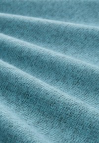 Zacht blauw stof met een gestructureerd, iets pluizig oppervlak, weergegeven in close-up plooien.