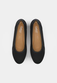 Ballerine nere con un esterno in tessuto liscio, punta rotonda e soletta imbottita color sabbia. Design minimalista con cuciture decorative.