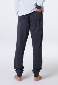 Pantaloni jogger grigio scuro realizzati in tessuto morbido, con una vestibilità rilassata, polsini elasticizzati e un dettaglio della tasca posteriore.