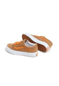 Des sneakers basses en suède beige présentent des accents orange, un design à lacets et une semelle en caoutchouc blanc avec une semelle extérieure texturée marron. Marquage classique affiché.