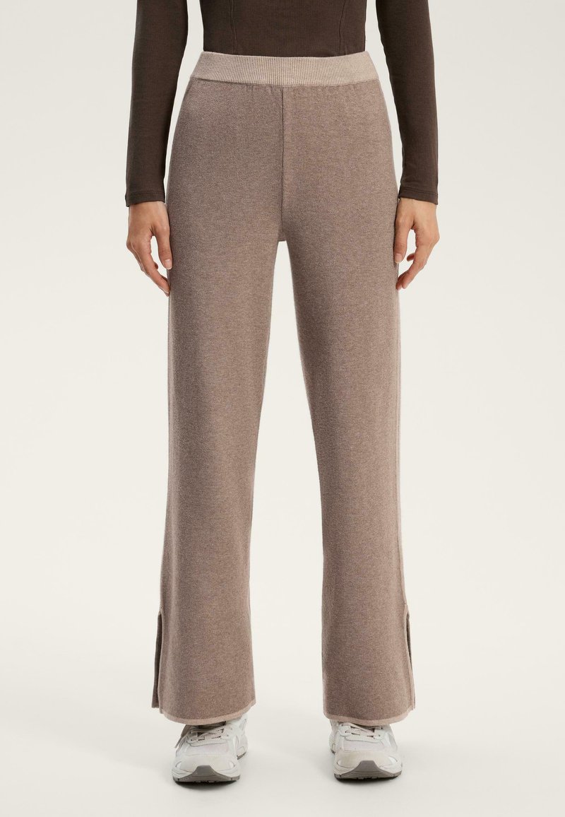 Pantaloni in maglia color beige chiaro con gamba ampia e fessure laterali all'orlo. Presenta una vita a costine a contrasto. Abbina a scarpe da ginnastica bianche.