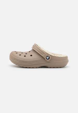 Beige klompen gemaakt van duurzaam materiaal, met een zachte fleece voering, ventilatiegaten voor ademend vermogen en een zijband voor het aanpassen van de pasvorm.