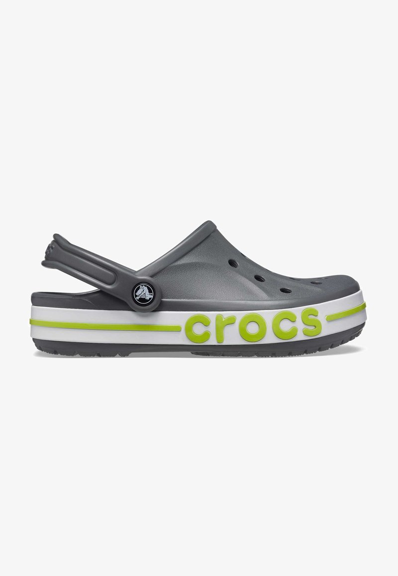 Des Crocs gris avec une semelle rayée blanche et verte, dotées de trous de ventilation, d'une sangle arrière et du logo "crocs" en vert sur le côté.