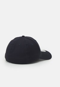 Boné de beisebol azul-marinho com uma coroa arredondada, aba ligeiramente curvada e costura visível. Feito de um tecido com uma textura suave.