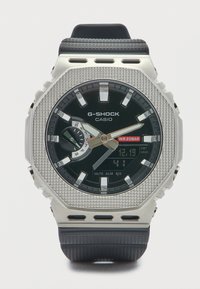 Ρολόι G-SHOCK Casio με μαύρο καντράν, ασημί εξάγωνη κάσα, λουράκι από καουτσούκ, αναλογική και ψηφιακή οθόνη, υφή στην κάσα και ανθεκτικό στο νερό μέχρι 200 μέτρα.