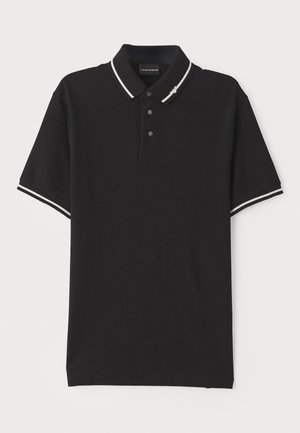 Polo negro de algodón con cuello, tapeta de tres botones y ribetes blancos en las mangas. Textura suave y corte estándar.