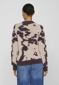 Pull en tricot moelleux de couleur beige clair avec un motif abstrait violet foncé, doté de poignets et d'un ourlet côtelés, d'un col rond et d'une coupe décontractée.