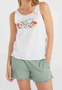 Biały top na ramiączkach z kwiatowym wzorem w kolorach różowym, pomarańczowym i zielonym; w połączeniu z miętowozielonymi szortami z falistym koronkowym wykończeniem na dole i bocznymi kieszeniami.