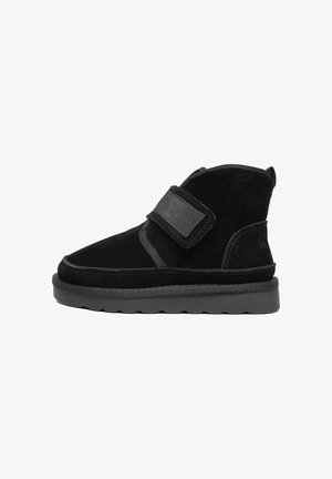 Schwarze Wildleder-Stiefeletten mit Klettverschluss, ausgestattet mit einer runden Zehenpartie, einer strukturierten Außenseite und einer flachen Gummisohle. Nähtedetails sind sichtbar.