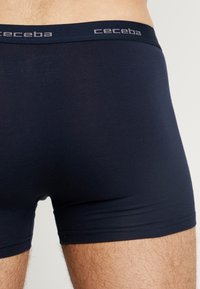 Dark navy boxer shorts made from a smooth, stretch fabric. Features a soft waistband with "ceceba" logo in grey.