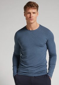 Pánská košile s dlouhým rukávem v tmavě modré barvě, vyrobená z měkké látky, s kulatým výstřihem a přiléhavými rukávy. Jednoduchý design, bez vzorů.