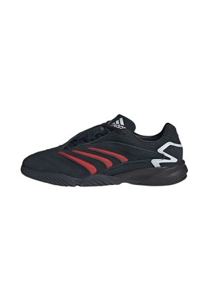 Zwarte Adidas sportschoen met rode zijstrepen en witte zigzagdetail op de hiel, gezien vanaf de buitenkant.