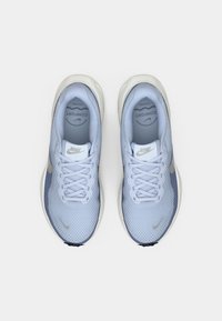 Par uštipa svijetloplavih Nike tenisica za trčanje s bijelim potplatima i vezicama, viđeno s gornje strane na jednostavnoj bijeloj pozadini.