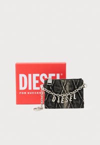 Μαύρο πορτοφόλι από καπιτονέ ύφασμα με ασημένια αλυσίδα, με την επιγραφή "DIESEL" σε μεταλλικά γράμματα· παρουσιάζεται με κόκκινο κουτί με λογότυπο.