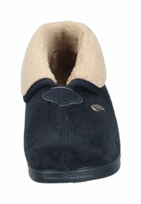 Nabend blauer Hausschuh mit einem beigen Kunstfellkragen, weichem Obermaterial, flacher schwarzer Gummisohle und einem kleinen metallischen Logo-Accessoire an der Seite.