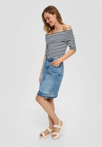 Off-shoulder gestreepte top in marineblauw en wit, gecombineerd met een lichtblauwe denim rok. Sandalen hebben dikke gevlochten banden en een chunky zool.