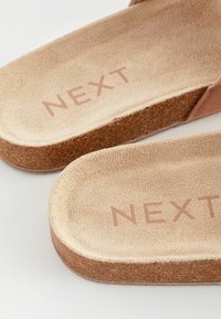 Korkové stélky ve světle hnědé barvě s texturovaným povrchem. Na jedné straně jsou opatřeny otiskem "NEXT". Okraje jsou zaoblené a hladké.