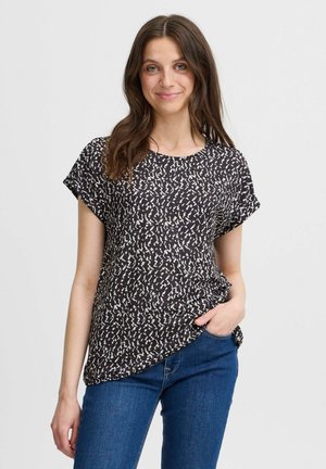 T-shirt noir à motif avec des formes abstraites blanches, col rond et manches courtes. Associé à un jean bleu. Tissu doux et léger.