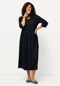 Granatowa sukienka do kolan z rękawami trzyczwartowymi, zebranym wcięciem w talii i dwiema przednimi kieszeniami. Miękka tkanina o luźnym kroju.