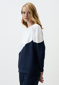 Marineblauwe en witte kleurblokken sweatshirt, met een ronde halslijn en een zachte textuur. Heeft lange mouwen en een ontspannen pasvorm.