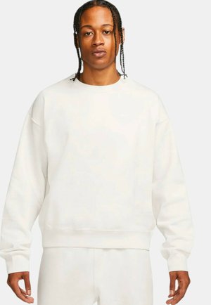 Hvid crewneck sweatshirt lavet af blødt stof, med løs pasform, ribbede mansjetter og en lille logo detalje på brystet.