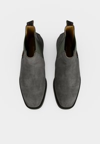 Paire de bottines Chelsea en daim gris avec panneaux latéraux élastiques et languettes, vues de dessus sur fond blanc.