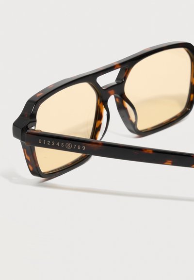 Tortoise shell sunglasses with rectangular beige lenses and a numeric sequence "0123456789" printed on the temple.